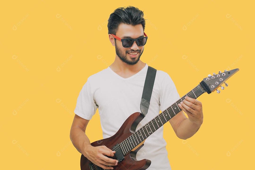 Bonitos jovens asiáticos tocando violão e ouvindo música com fones de ouvido isolados em fundo amarelo