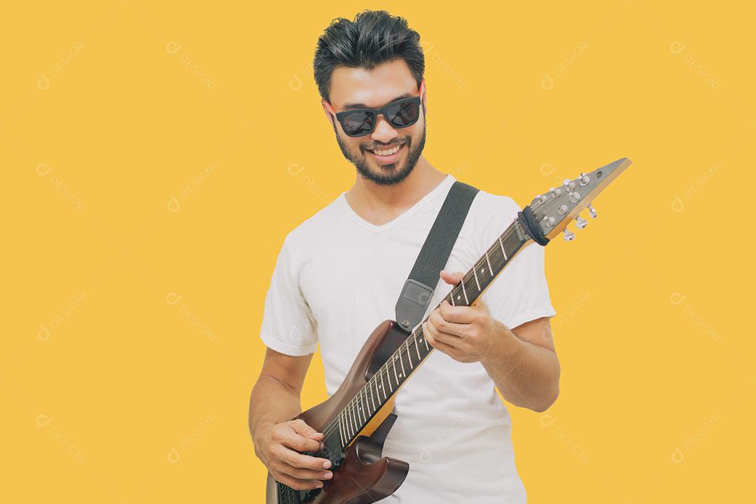 Bonitos jovens asiáticos tocando violão e ouvindo música com fones de ouvido isolados em fundo amarelo