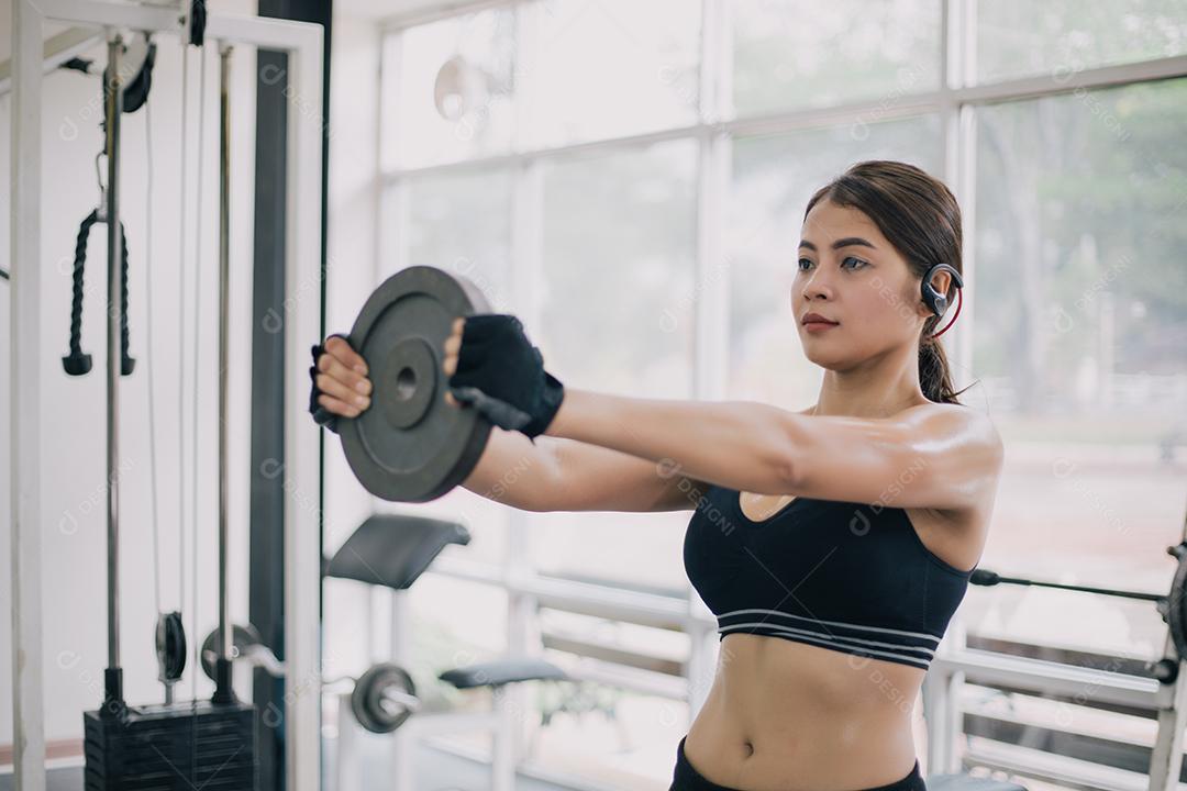 bela mulher apto muscular exercitando a construção de músculos e fitness mulher fazendo exercícios no ginásio. Aptidão - conceito de estilo de vida saudável