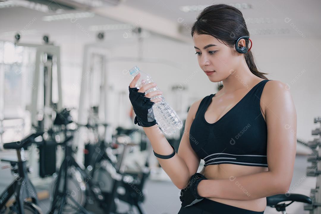 Água potável da Ásia mulher desportiva após exercícios no ginásio. Aptidão - conceito de saudável