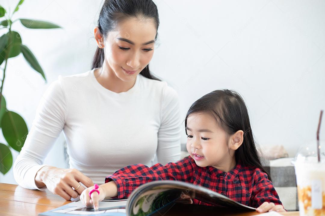 Mamãe está ensinando sua filha a ler um livro.