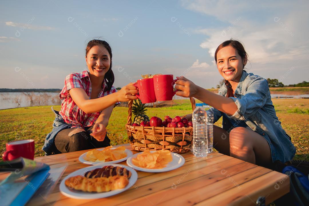 Um grupo de amigos asiáticos bebendo café e passando o tempo fazendo um piquenique nas férias de verão. Eles estão felizes e se divertem nos feriados.