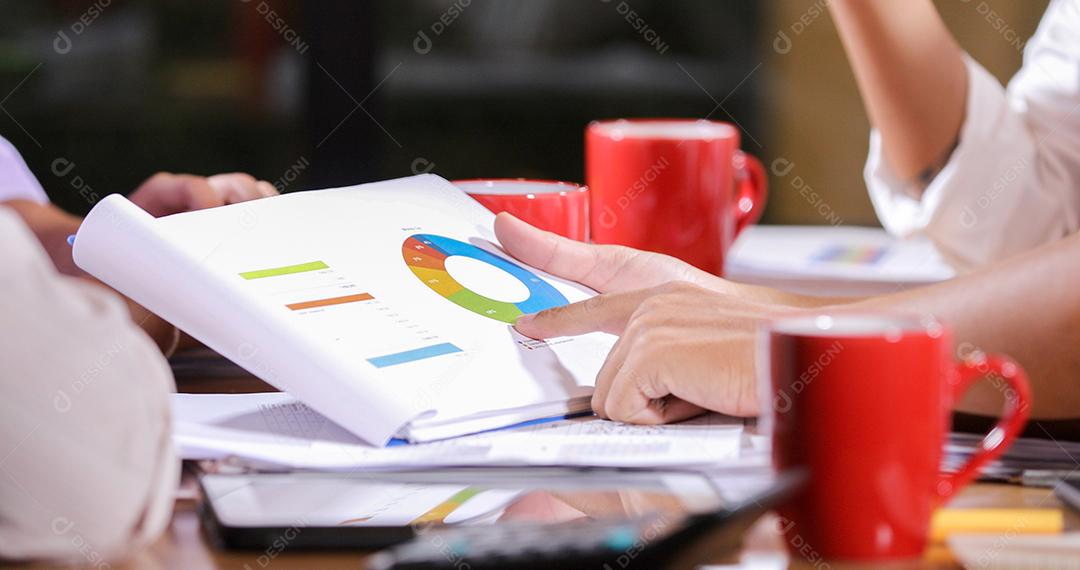 Documentos de análise de empresárias asiáticas na mesa de escritório com computador portátil e diagrama financeiro gráfico trabalhando em segundo plano