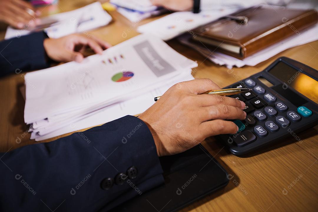 Empresários estão usando calculadoras e dados de negócios de análise e diagrama financeiro gráfico trabalhando na reunião.