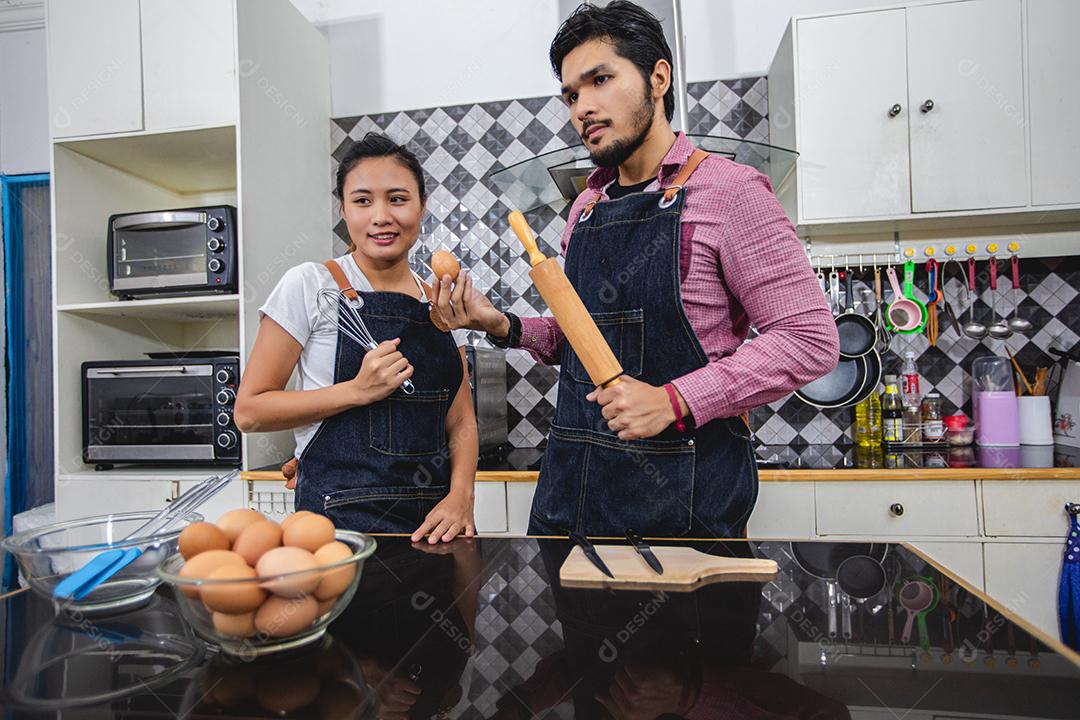 Feliz e sorridente jovem casal cozinhando comida na cozinha em casa