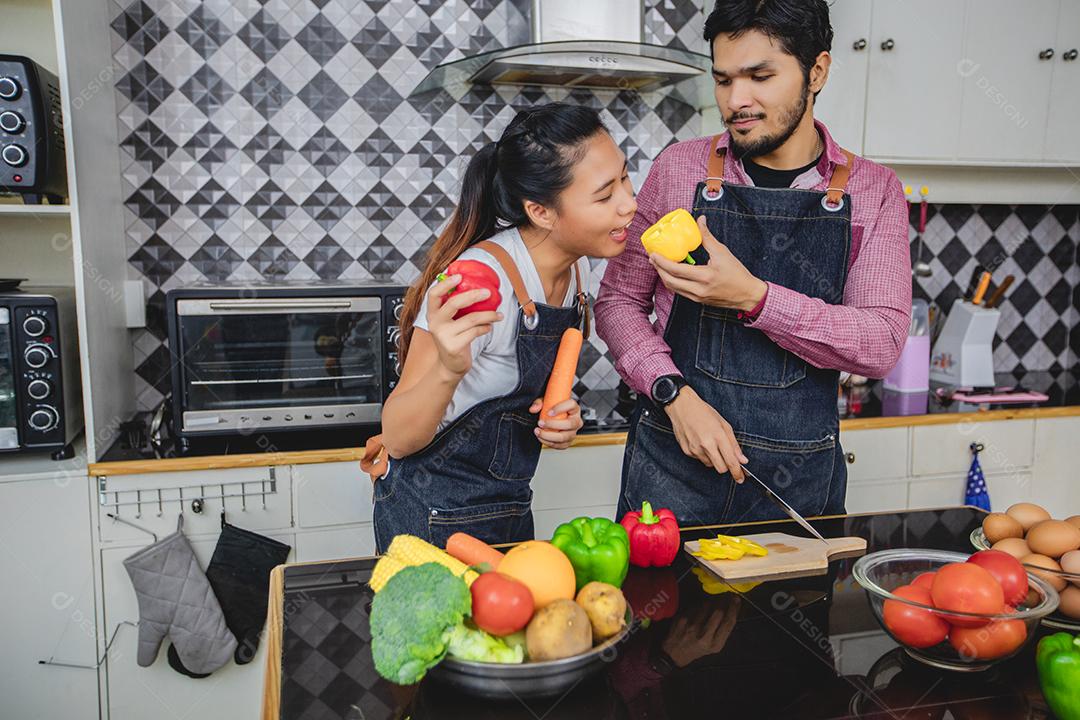 Feliz e sorridente jovem casal cozinhando comida na cozinha em casa