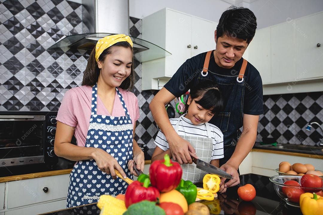 Família feliz tem papai, mamãe e sua filhinha cozinhando juntos na cozinha