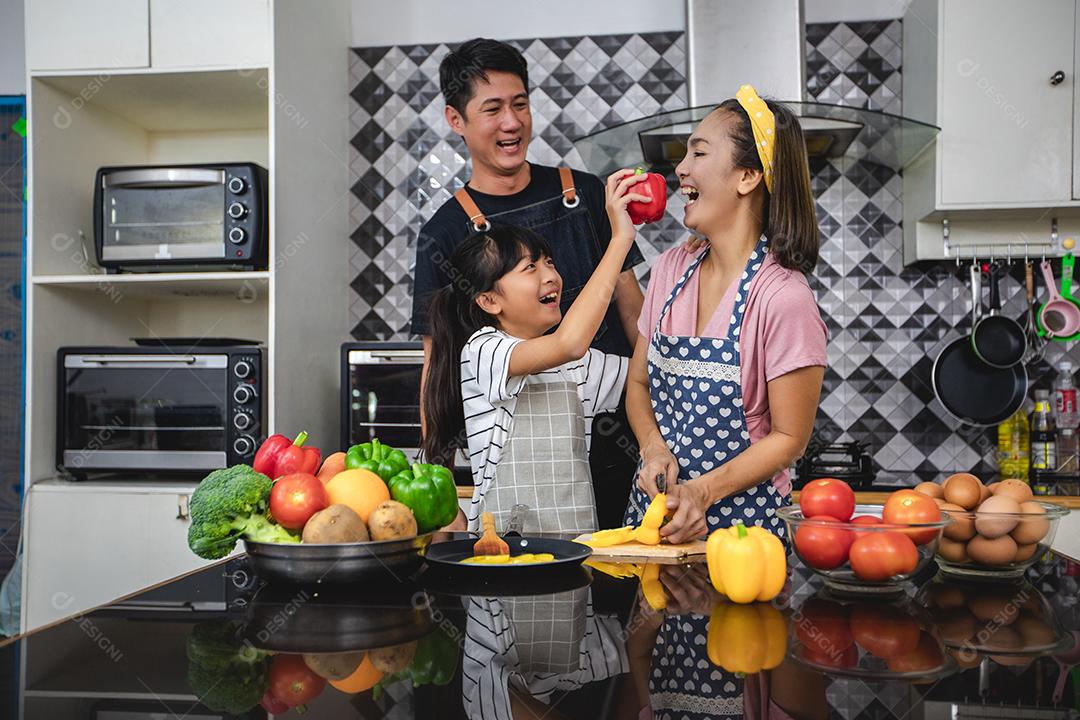 Família feliz tem papai, mamãe e sua filhinha cozinhando juntos na cozinha