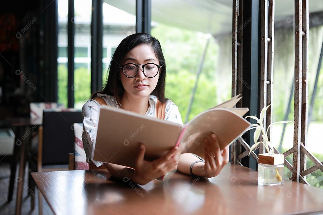Menu aberto de mulher asiática para pedir no café e restaurante e sorrindo para um momento feliz
