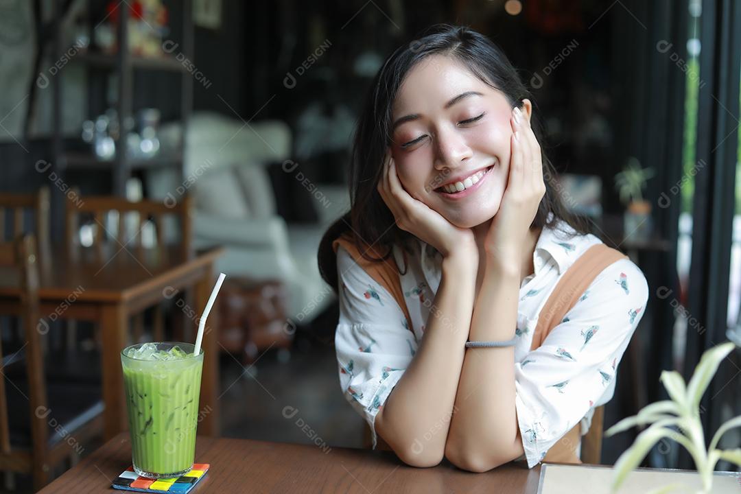 Asian women smiling and happy Relaxing with green tea in a coffee shop