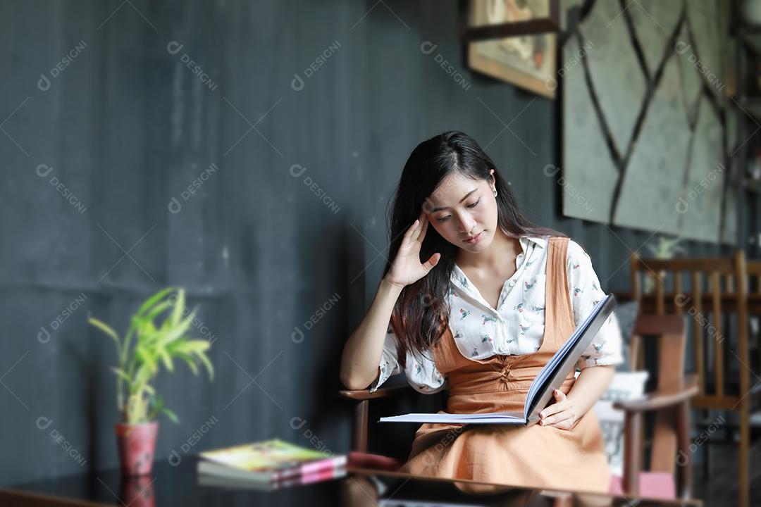 Mulheres asiáticas lendo livro e sorrindo e felizes Relaxando em uma cafeteria