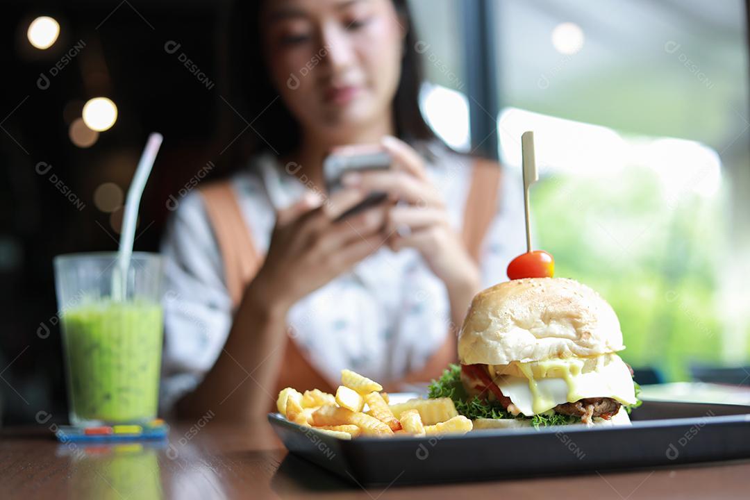 Mulheres asiáticas sorrindo e felizes e gostando de comer hambúrgueres no café e restaurante na hora do relaxamento