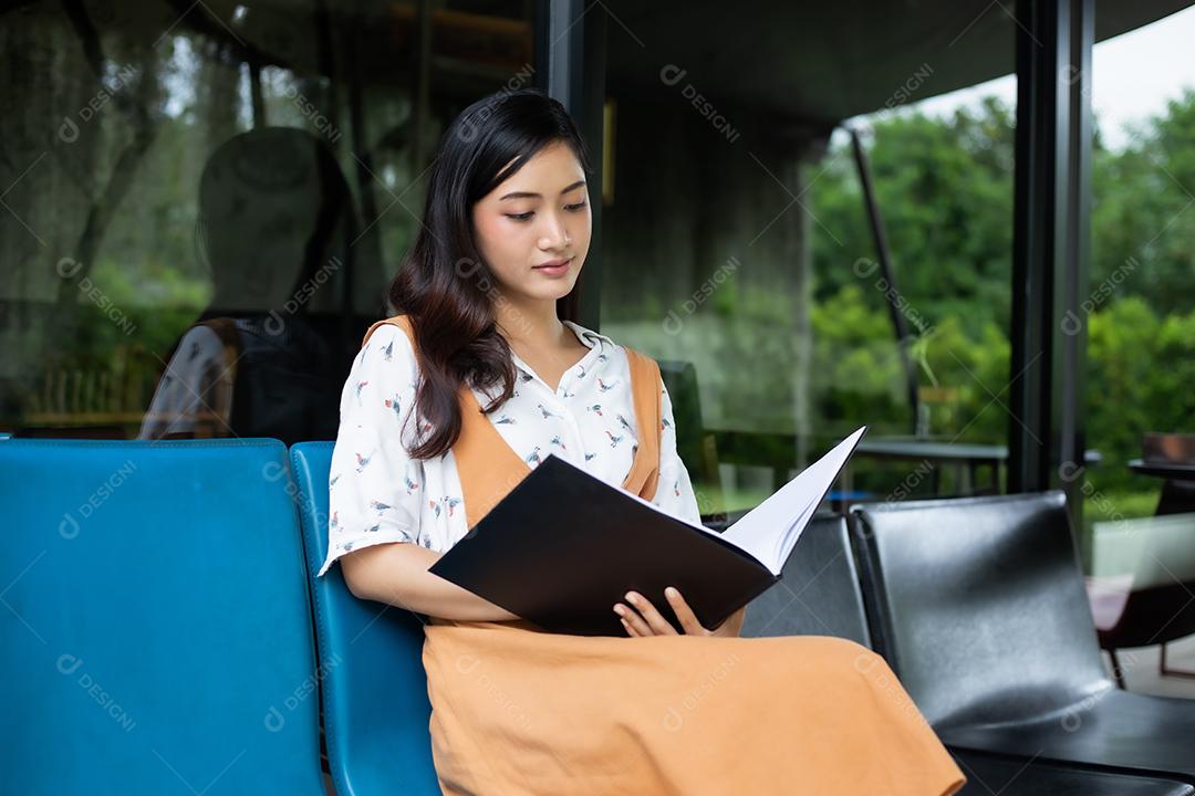 Mulheres asiáticas lendo livro e sorrindo e felizes Relaxando em uma cafeteria