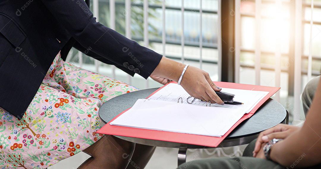 A mulher agente está segurando o carro-chave para esperar para dar depois que os empresários assinarem um contrato de compra de carro.