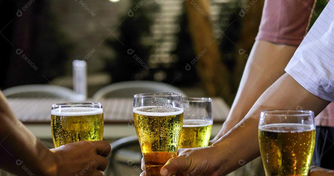 Grupo asiático de amigos festejando com bebidas alcoólicas de cerveja e jovens desfrutando em um bar brindando coquetéis e copos tinindo