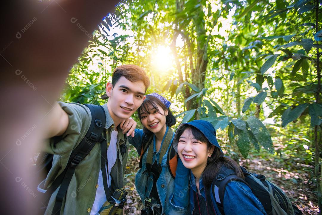 Grupo asiático de jovens com amigos e mochilas caminhando juntos e amigos felizes estão tirando fotos e selfies, relaxe o tempo em viagens de conceito de férias