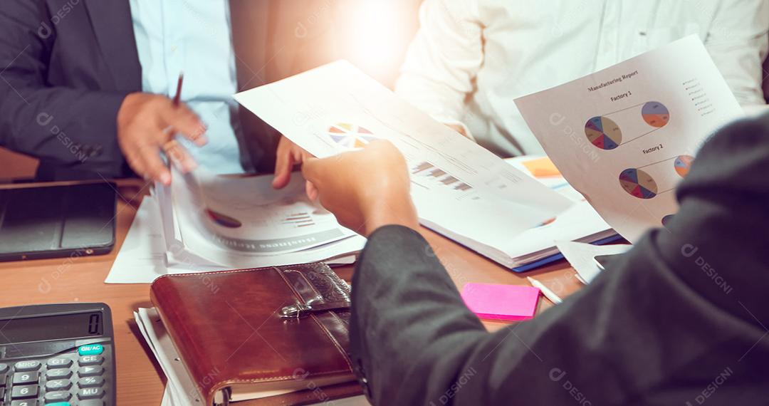 Empresários asiáticos e empresárias analisam documentos na mesa de escritório com computador portátil e diagrama financeiro gráfico trabalhando em segundo plano