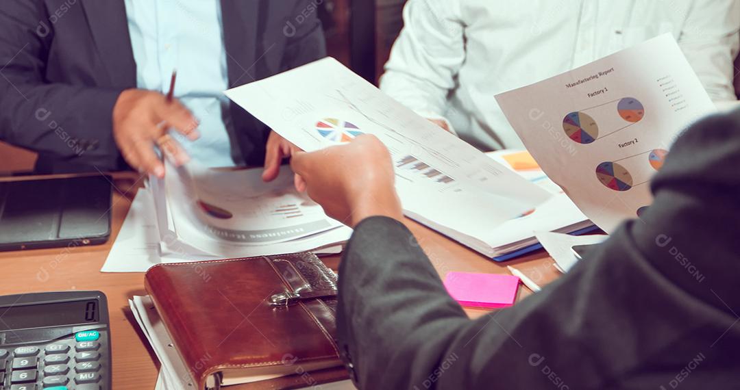 Empresários asiáticos e empresárias analisam documentos na mesa de escritório com computador portátil e diagrama financeiro gráfico trabalhando em segundo plano