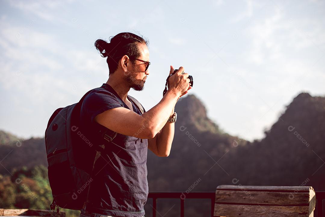 Mochilas de homens asiáticos e viajantes caminhando juntos e felizes estão tirando fotos na montanha, relaxe o tempo em viagens de conceito de férias