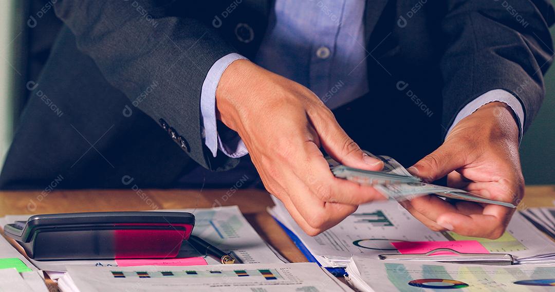 Empresários contam dinheiro e planejam finanças para projetos e usam calculadoras para análise de documentos de projetos e diagrama financeiro gráfico trabalhando em segundo plano na mesa de escritório