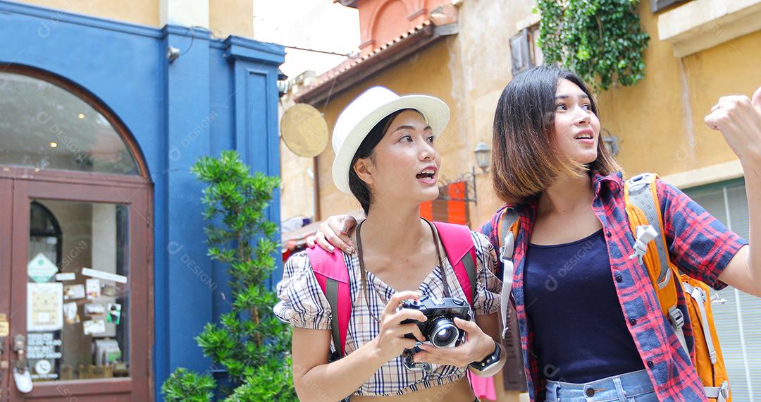 Mochilas de mulheres asiáticas caminhando juntas e felizes estão tirando fotos e olhando fotos, relaxe o tempo em viagens de férias