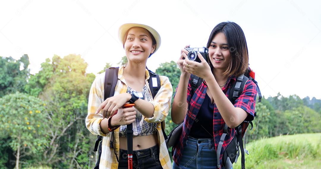 Grupo asiático de jovens Caminhando com mochilas de amigos caminhando juntos e olhando o mapa e tirando a câmera fotográfica pela estrada e parecendo feliz, Relaxe o tempo em viagens de conceito de férias