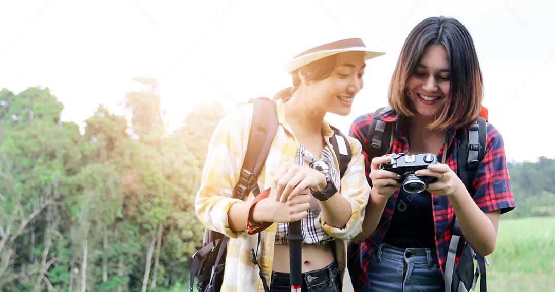 Grupo asiático de jovens Caminhando com mochilas de amigos caminhando juntos e olhando o mapa e tirando a câmera fotográfica pela estrada e parecendo feliz, Relaxe o tempo em viagens de conceito de férias