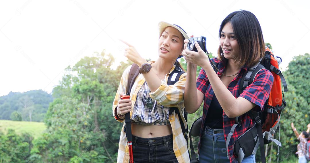 Grupo asiático de jovens Caminhando com mochilas de amigos caminhando juntos e olhando o mapa e tirando a câmera fotográfica pela estrada e parecendo feliz, Relaxe o tempo em viagens de conceito de férias