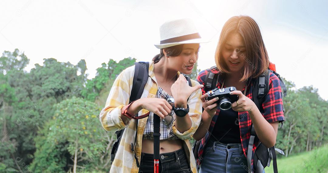 Grupo asiático de jovens Caminhando com mochilas de amigos caminhando juntos e olhando o mapa e tirando a câmera fotográfica pela estrada e parecendo feliz, Relaxe o tempo em viagens de conceito de férias