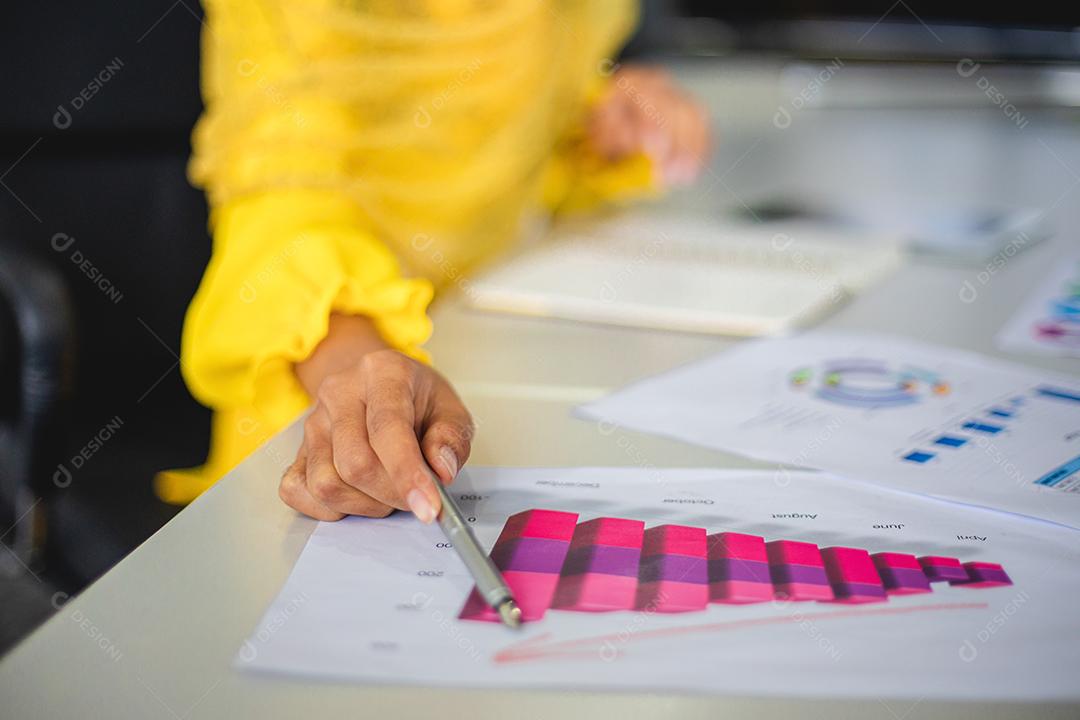 Empresárias muçulmanas analisam documentos na mesa do escritório e têm diagrama financeiro gráfico trabalhando em segundo plano