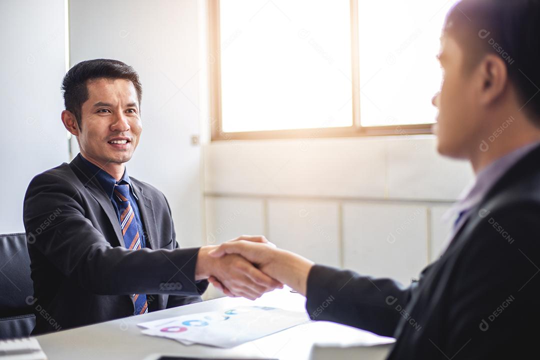 Empresários apertando as mãos e sorrindo seu acordo para assinar contrato e terminar uma reunião