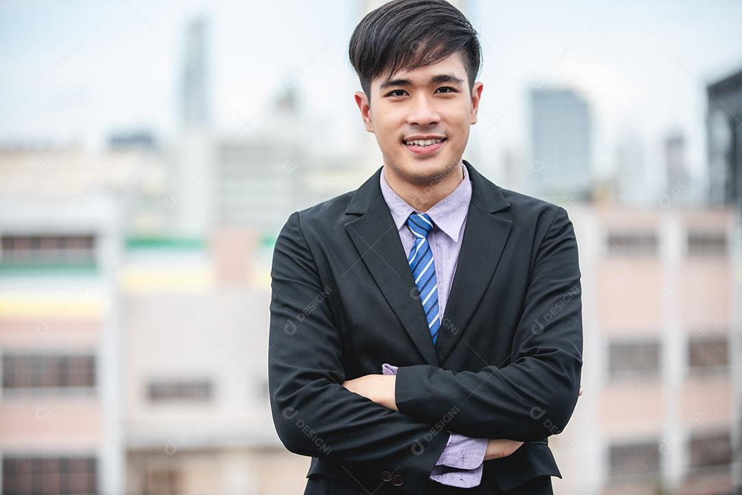 Feliz empresário bonito de pé e sorrindo ao ar livre