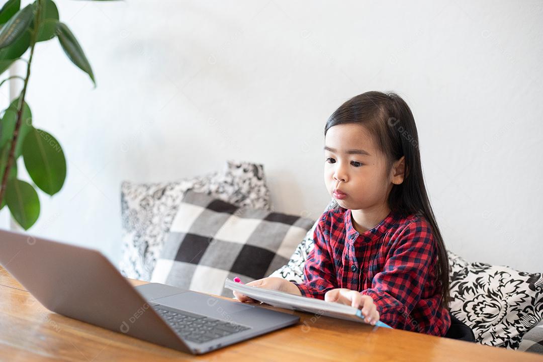 As crianças lêem um livro e um notebook assistindo.