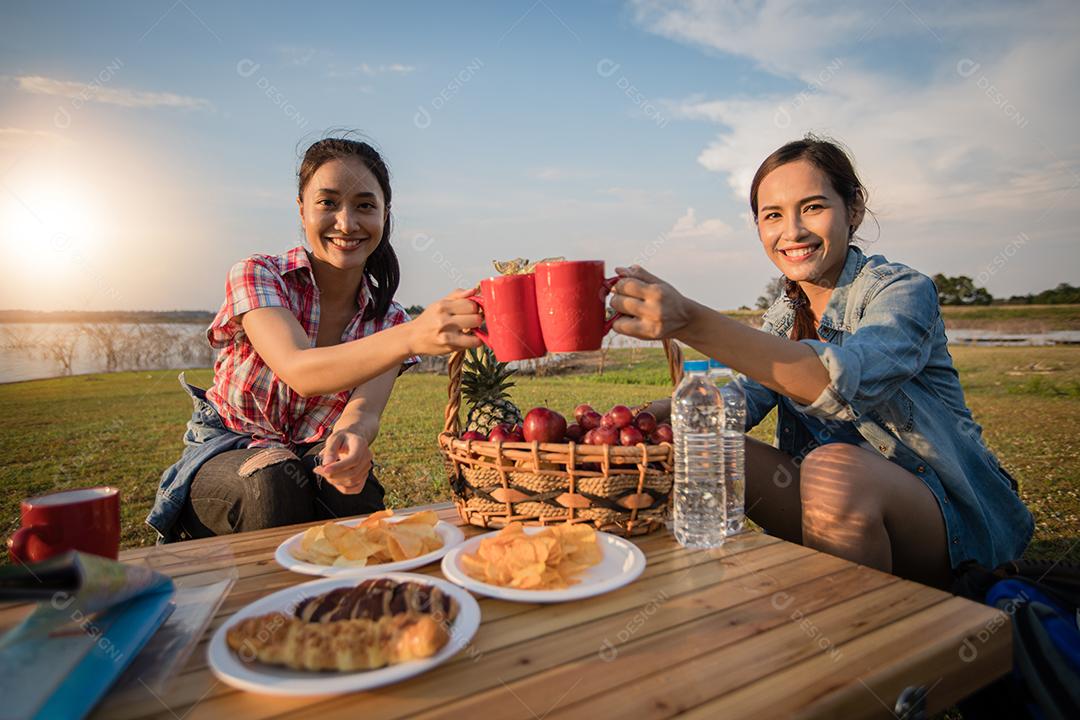 Um grupo de amigos asiáticos bebendo café e passando o tempo fazendo um piquenique nas férias de verão. Eles estão felizes e se divertem nos feriados.