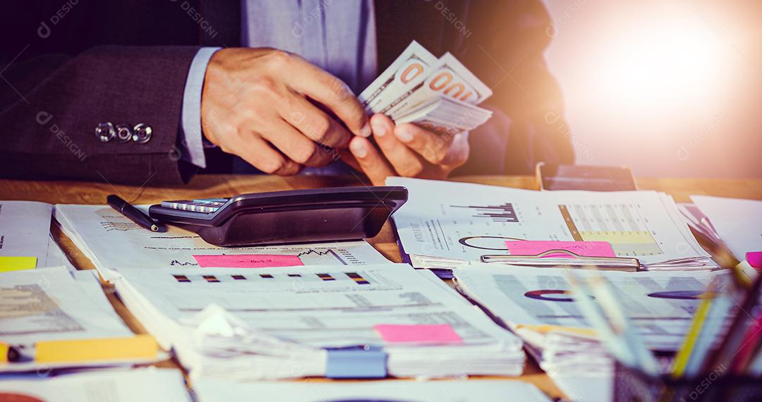 Empresários contam dinheiro e planejam finanças para projetos e usam calculadoras para análise de documentos de projetos e diagrama financeiro gráfico trabalhando em segundo plano na mesa de escritório