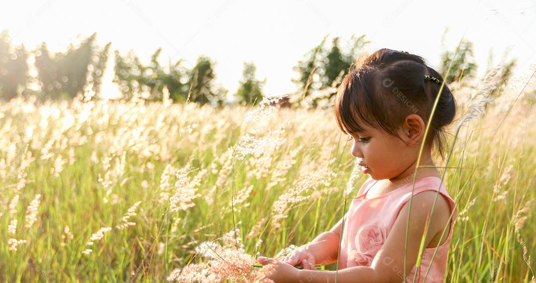 Menina asiática rindo e feliz no prado no verão na natureza