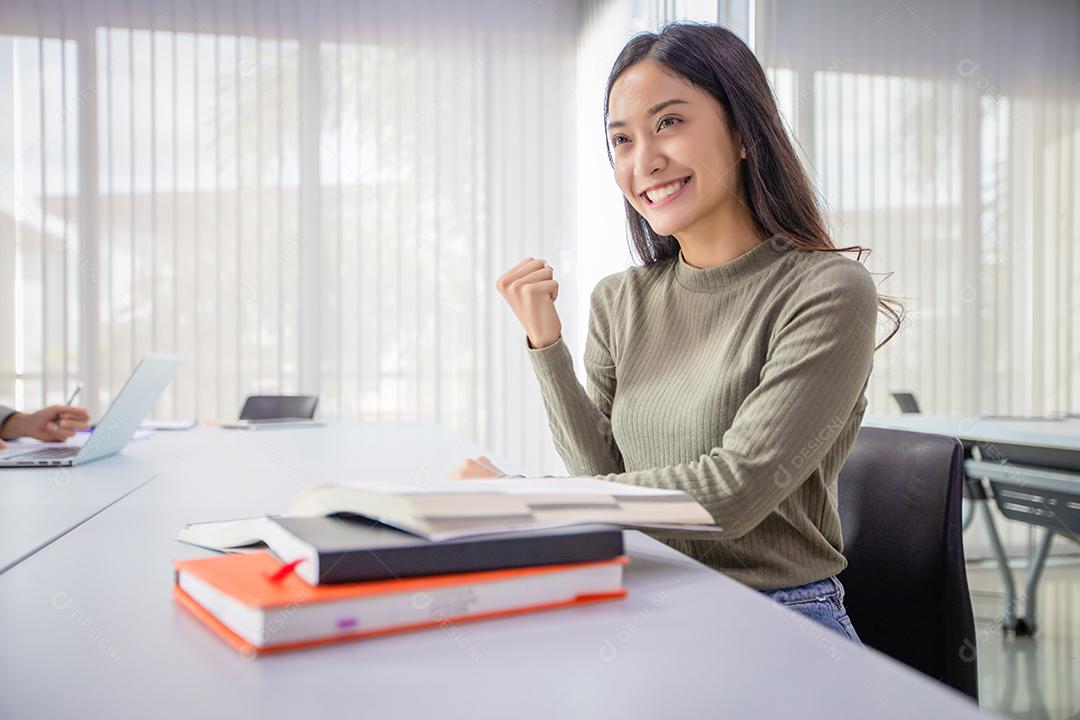 Mulher asiática Estudante Sorriem e Animadas com os braços levantados Ela lendo o livro E também revisando o livro antes do exame