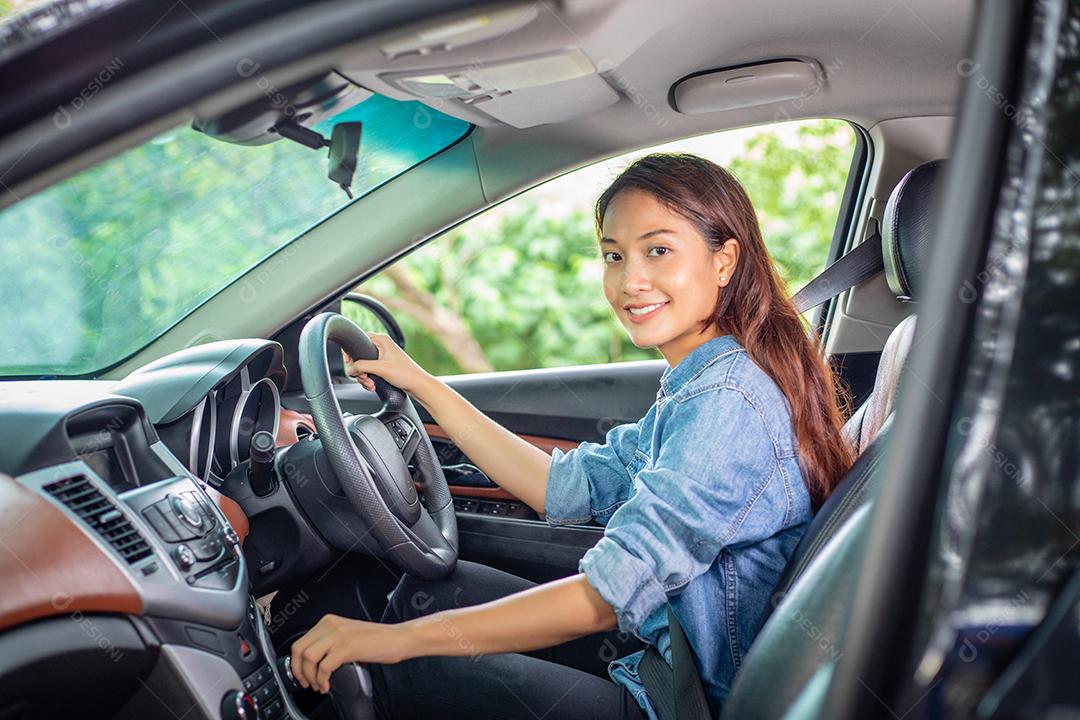 Linda mulher asiática sorrindo e se divertindo dirigindo um carro na estrada para viajar