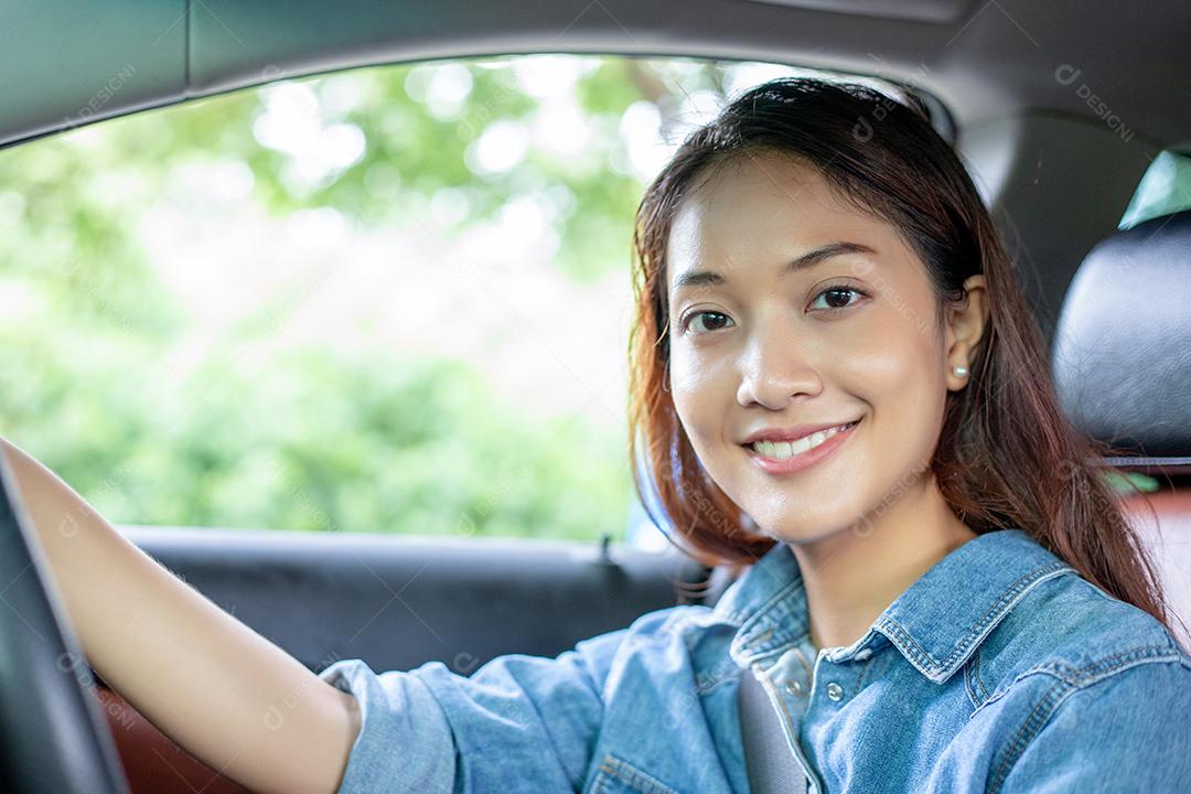 Linda mulher asiática sorrindo e se divertindo dirigindo um carro na estrada para viajar