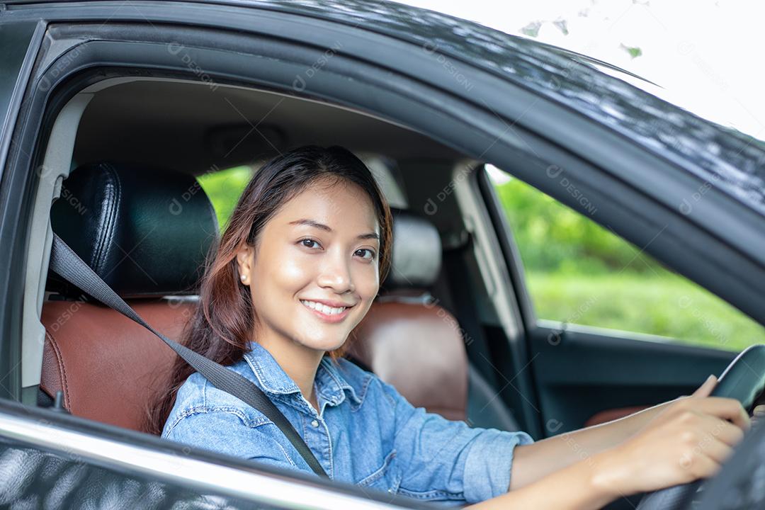 Linda mulher asiática sorrindo e se divertindo dirigindo um carro na estrada para viajar