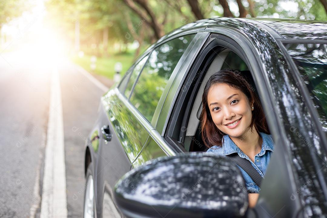 Linda mulher asiática sorrindo e se divertindo dirigindo um carro na estrada para viajar