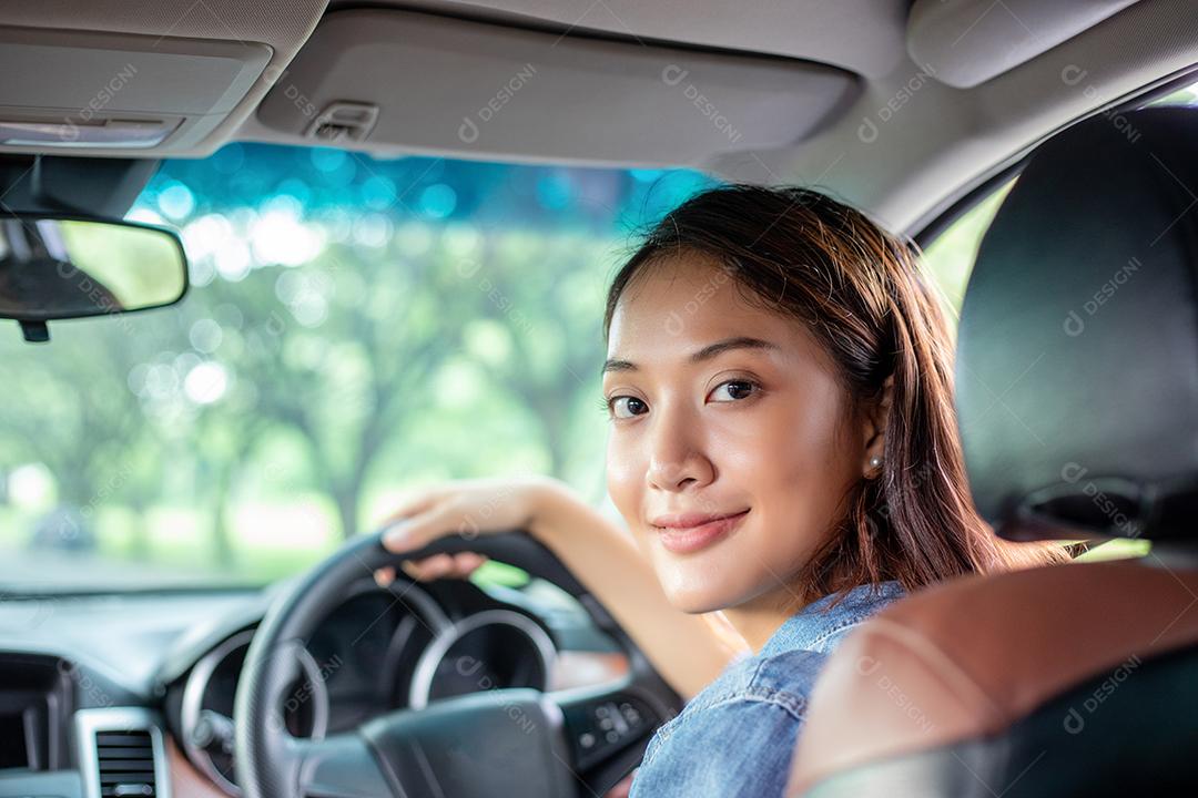 Linda mulher asiática sorrindo e se divertindo dirigindo um carro na estrada para viajar