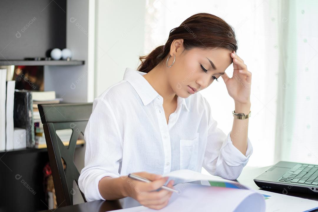 Mulher de negócios asiática séria e dor de cabeça sobre o trabalho duro e o uso do notebook