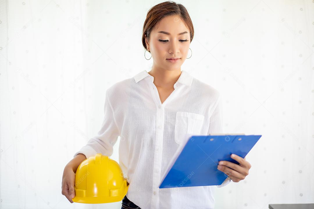 Mulheres asiáticas engenharia inspecionando e trabalhando e segurando plantas no escritório ela está sorrindo feliz pelo trabalho