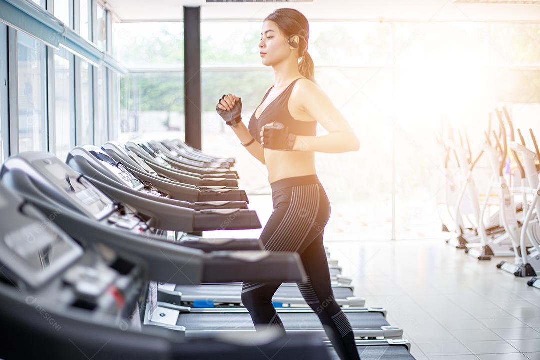 Mulheres asiáticas correndo sapatos esportivos na academia enquanto uma jovem caucasiana está correndo na esteira