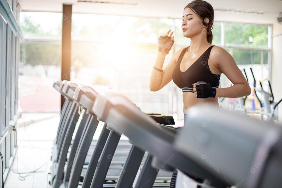 Mulheres asiáticas correndo sapatos esportivos na academia enquanto uma jovem caucasiana está correndo na esteira