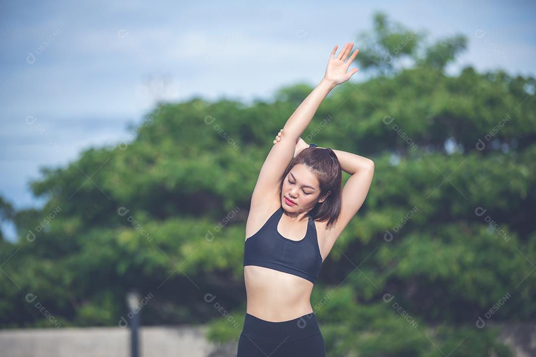 Mulher atlética asiática se aquecendo e jovem atleta sentada em um exercício e alongamento em um parque antes do corredor ao ar livre, conceito de estilo de vida saudável