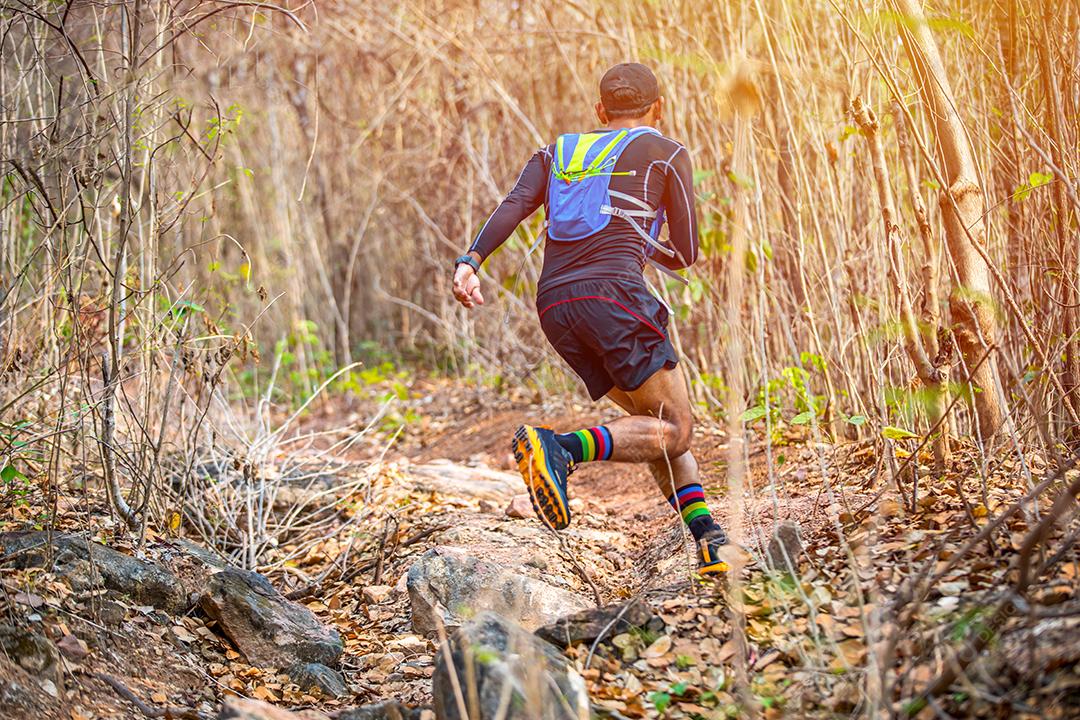 Um homem Runner of Trail e pés de atleta usando sapatos esportivos para trilha na floresta