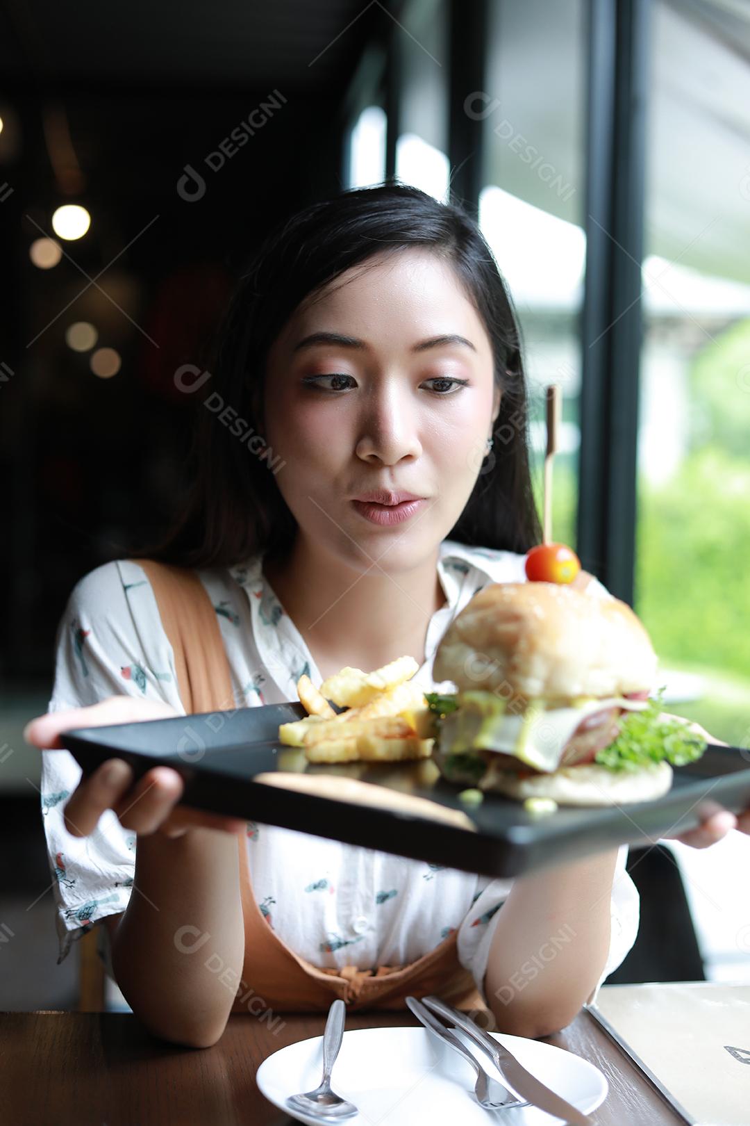 Mulheres asiáticas tirando fotos de hambúrgueres e gostando de comer no café e restaurante na hora do relaxamento