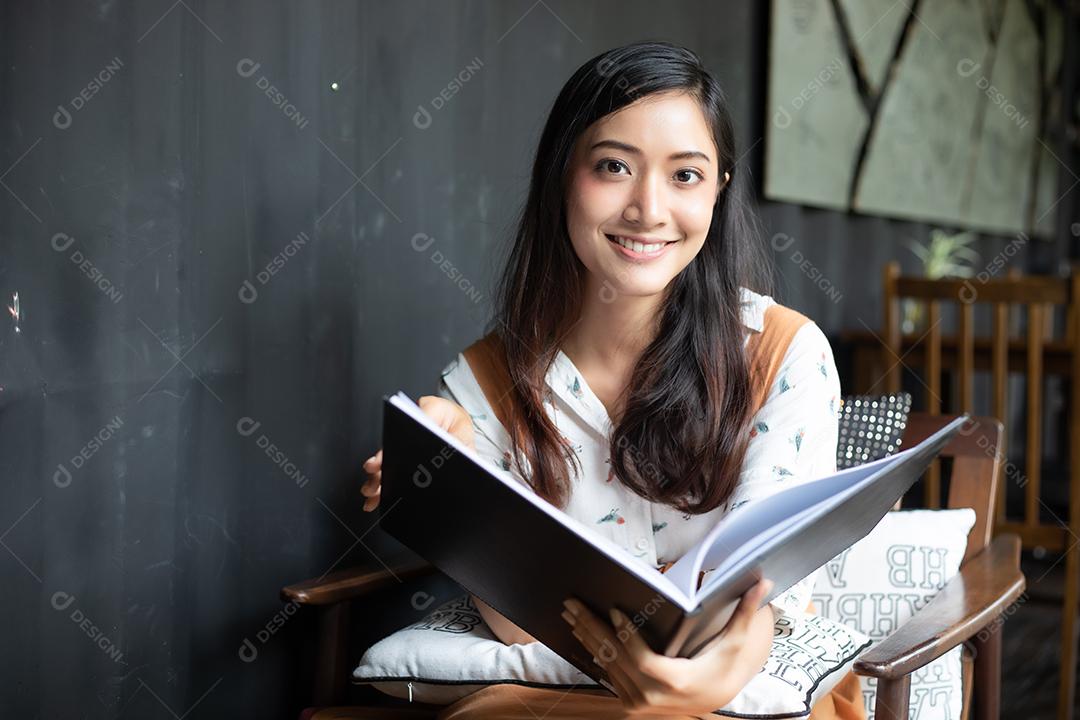 Mulheres asiáticas lendo e sorrindo e felizes Relaxando em uma cafeteria depois de trabalhar em um escritório de sucesso.